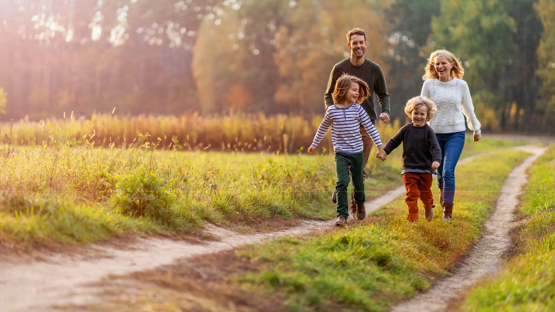 A family of four hikes a trail in a green landscape.